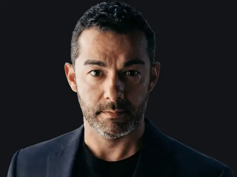 Michael Uvalle, founding attorney of LAWBOSS, Uvalle Law Firm, PLLC, in a dark blazer and black T-shirt against a dark background